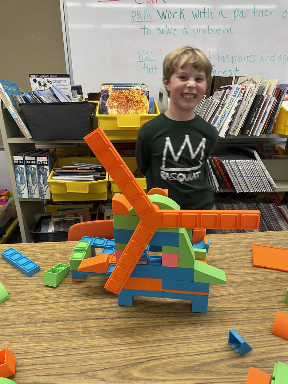 A child displaying a colorful windmill made with building blocks