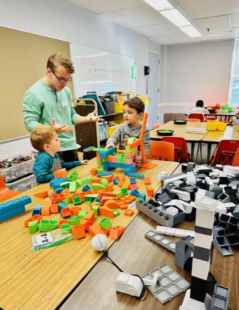 Students collaboratively building at classroom tables