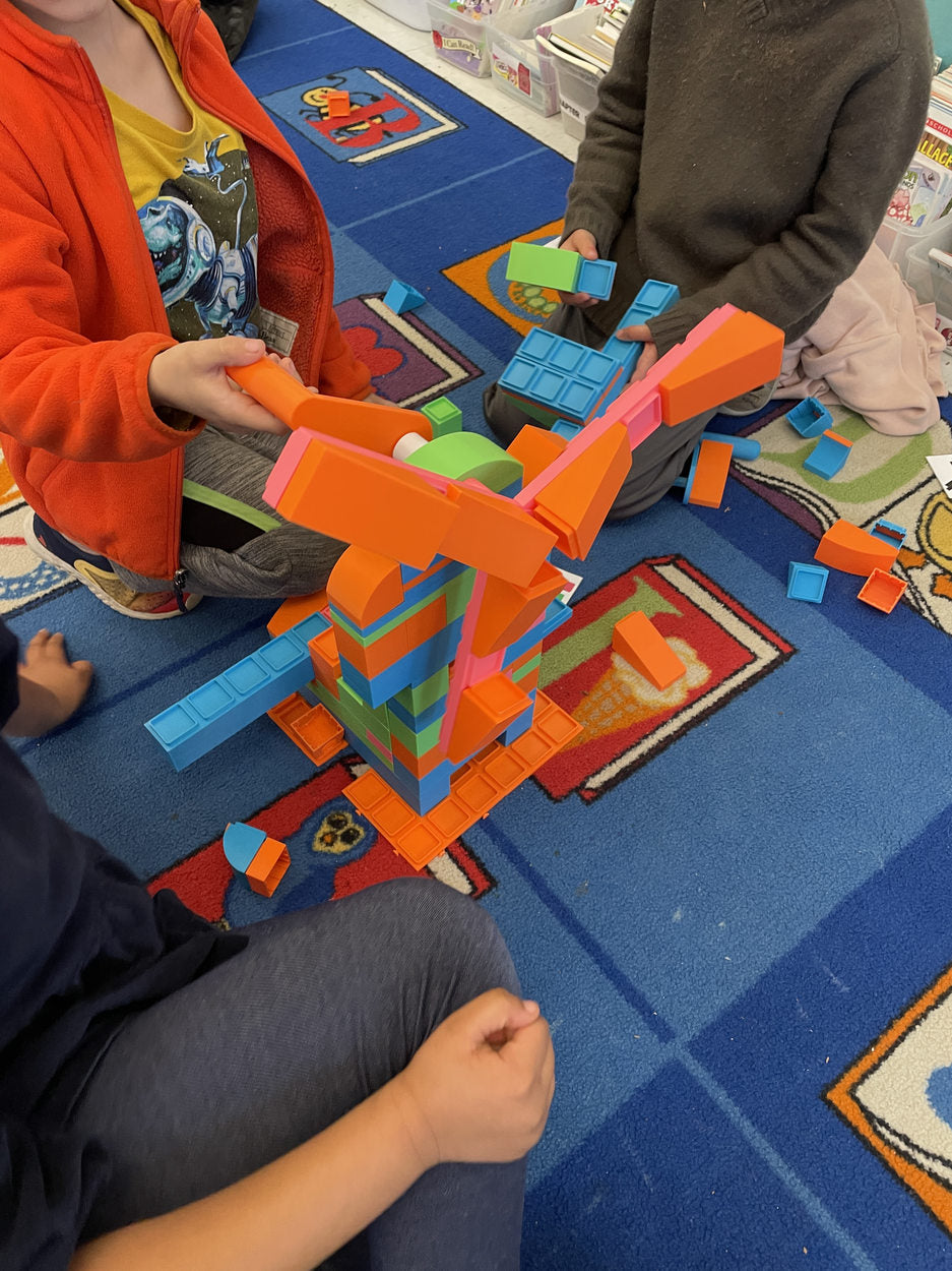 Students experimenting together with an orange-and-blue build